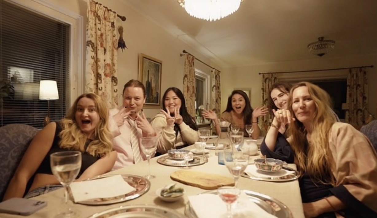 A long dinner table of friends and founders gathered together, laughing