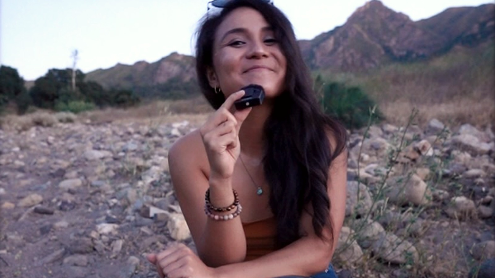Ysabel Chavez sitting in a quiet mountain landscape at dusk